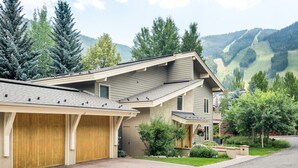 Een modern huis met twee verdiepingen, een garage, een overdekte oprit en een verzorgd gazon.