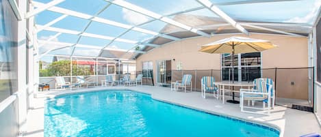 A covered swimming pool with lounge chairs and umbrellas.