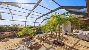 A covered outdoor area with lounge chairs, a small pool, and potted plants. - Villa Portofino: Resort Style Pool, Gulf Access (Cape Coral)