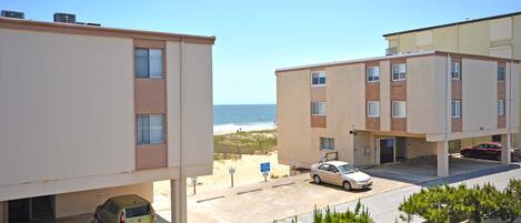 Ein Wohnhaus an der Küste mit Parkplatz, Blick auf den Strand und einer kleinen Tiefgarage.