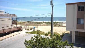 A beachfront property with a wooden deck, a sandy beach, and a view of the ocean. - Cute, casual 2-bedroom condo with free WiFi and a partial ocean view located midtown and less than a block to the beach! (Ocean City)