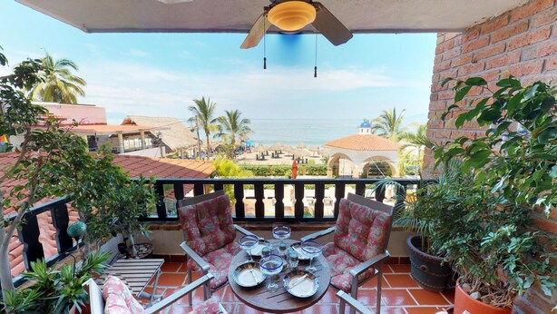 A balcony with a table set for dining, overlooking a beach and a building with a blue dome. - Bienvenido Amigo! In the heart of Amapas  2BD Condo for rent in Old Town, Puerto (Puerto Vallarta)