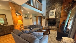 Una sala de estar acogedora con un sofá gris, una chimenea y una pared de piedra.