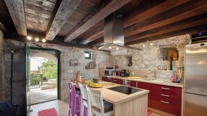 A rustic kitchen with stone walls, wooden beams, and a central island with stools. - Best host 2025 - 19th Century Stone Art Villa - Pool & 360° Sea View terrace (Makarska)