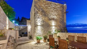A stone building with a balcony overlooking the sea, outdoor seating, and potted plants. - Best host 2025 - 19th Century Stone Art Villa - Pool & 360° Sea View terrace (Makarska)