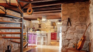 A rustic kitchen with stone walls, wooden beams, and a bar area with bar stools. - Best host 2025 - 19th Century Stone Art Villa - Pool & 360° Sea View terrace (Makarska)