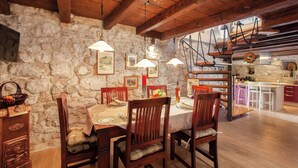 A rustic dining area with stone walls, wooden beams, and a kitchen in the background. - Best host 2025 - 19th Century Stone Art Villa - Pool & 360° Sea View terrace (Makarska)