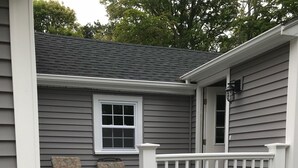 A house with a porch, two chairs, and a small window.