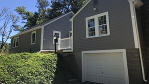 A two-story house with a white garage door and a small porch with a railing.