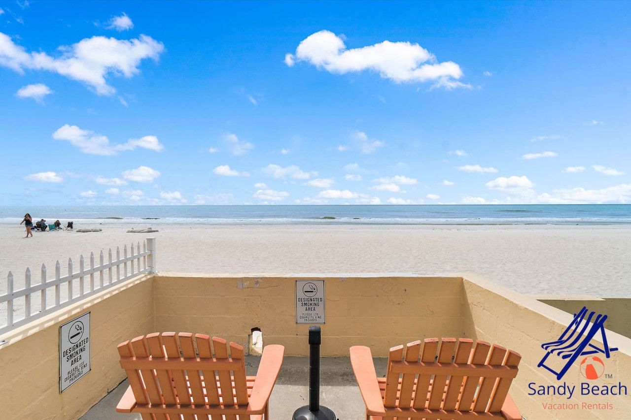 Uitzicht op het strand met aangewezen rookzones en een bord voor Sandy Beach Vacation Rentals.