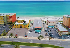 A coastal hotel with a parking lot, beach view, and multiple buildings.