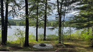 A lakeside view with a wooden deck and a picnic table. - Waterfront Chalet with private beach in the White Mountains of New Hampshire. (Conway)