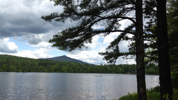 A calm lake with a forested shoreline and a mountain in the background. - Waterfront Chalet with private beach in the White Mountains of New Hampshire. (Conway)
