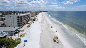 Un hotel sulla spiaggia con diversi piani, una spiaggia sabbiosa e vista sull'oceano.