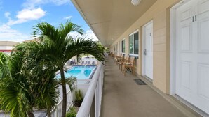 Un balcone con piscina, sedie e porte.