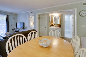 Cozy living space with a round dining table, mounted TV, and comfortable sofa.