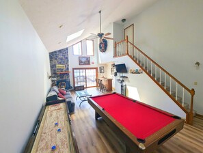 Uma mesa de bilhar, um sofá, uma escada e uma parede de pedra.