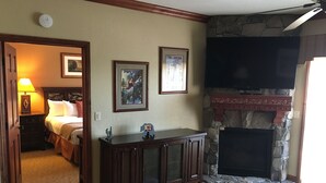 Una habitación de hotel con cama, televisión, chimenea y escritorio.
