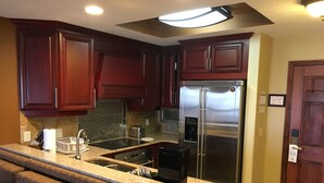 Una cocina con armarios de madera oscura, electrodomésticos de acero inoxidable, encimera de granito y horno empotrado.