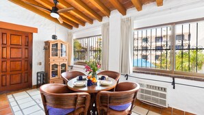 A dining area with a round table, wicker chairs, and a ceiling fan. - Condo in Olas Altas 1  1BD Studio for rent in Old Town, Puerto vallarta (Puerto Vallarta)
