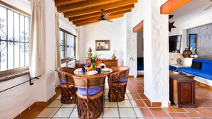 A dining area with a wooden ceiling, a dining table with chairs, and a view of the living room with a blue sofa. - Condo in Olas Altas 1  1BD Studio for rent in Old Town, Puerto vallarta (Puerto Vallarta)