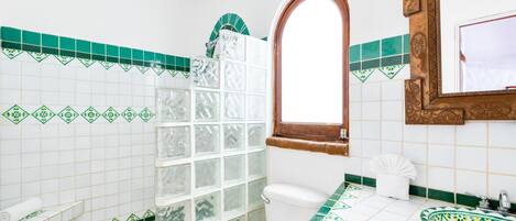 A bathroom with a toilet, a sink, and a shower area.