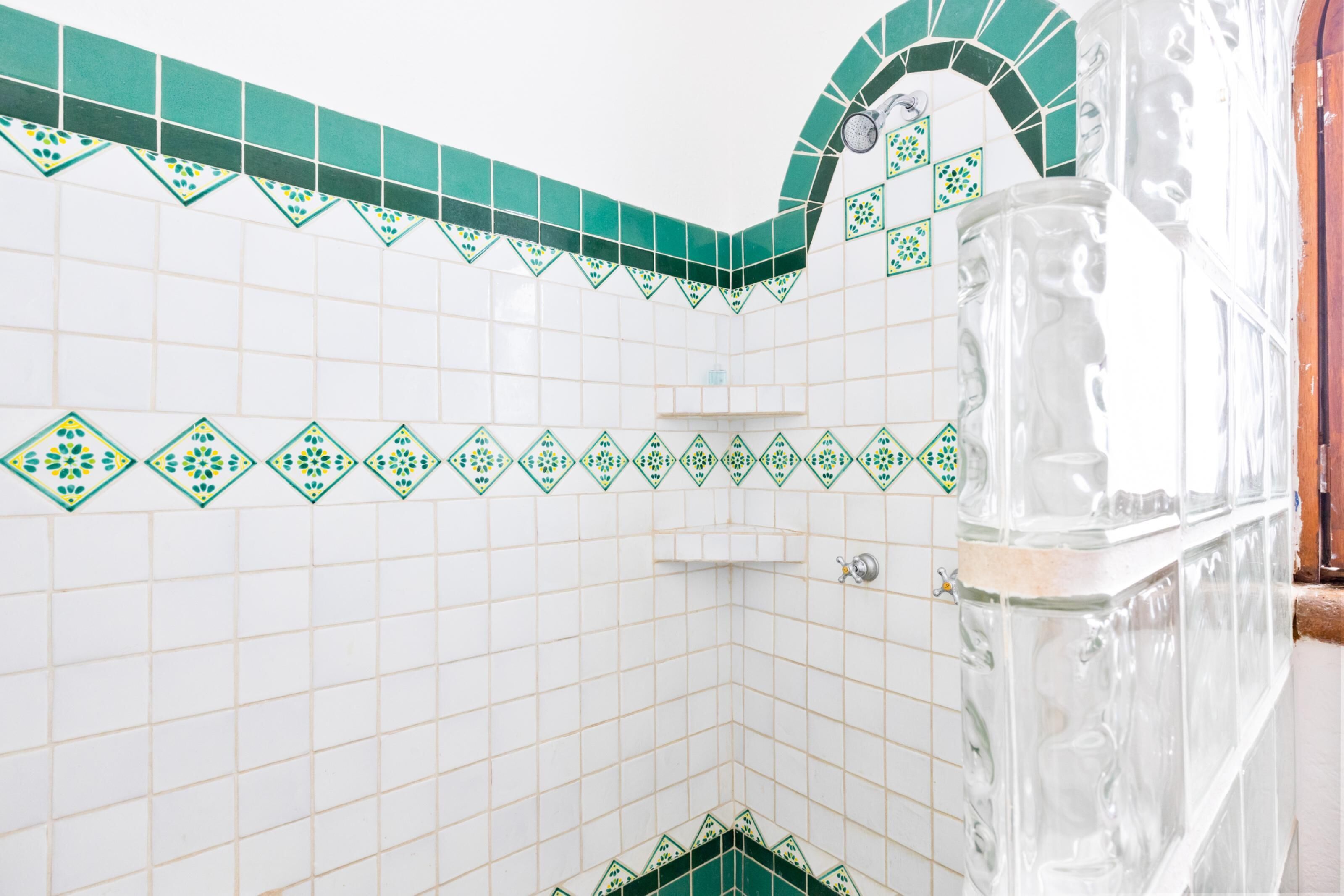 Een badkamer met witte betegelde wanden en groene decoratieve tegels langs de randen.