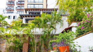 A multi-story building with balconies, surrounded by lush greenery and flowering plants. - Condo in Olas Altas 1  1BD Studio for rent in Old Town, Puerto vallarta (Puerto Vallarta)