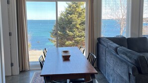 Un coin repas avec une table et des chaises, un canapé et une vue sur la mer.