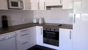 A compact kitchen with white cabinets, a microwave, a toaster, and an oven. - Toogooloowa on Davey 3 (Hobart)