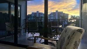 Ein Balkon mit Blick auf einen Sonnenuntergang über einer Stadtlandschaft.