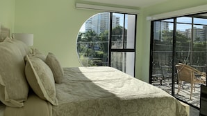 Ein Schlafzimmer mit Bett, einem Fenster und einem Balkon mit Stühlen.