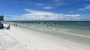 Ein Strand mit blauem Himmel und lockeren Wolken.