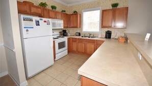 Una cocina con armarios de madera, un refrigerador, una estufa y un ventanal.
