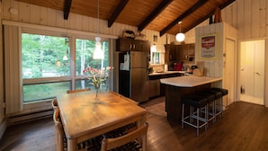 Un intérieur en bois comprenant un coin cuisine, une table à manger et des tabourets de bar.