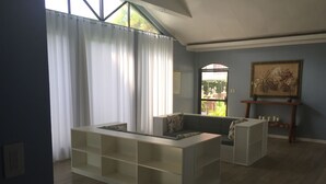 Un salón espacioso con una estantería blanca empotrada, un sofá de color oscuro y un cuadro en la pared.