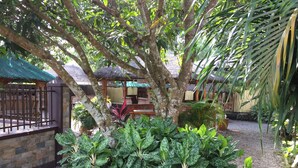Un jardín con diversas plantas y una zona de estar con techo de paja.