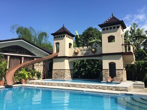 Entrada de un resort con piscina, destacándose un letrero con figuras de leones y el nombre 'BellaVista Resort'.