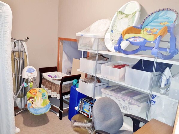 A baby changing station with a high chair, a baby seat, and storage shelves.