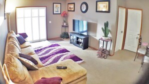 A living room with a sofa, a TV, a cactus, and a door. - Bright, Welcoming Mountain Escape! Near Downtown! (Calgary)