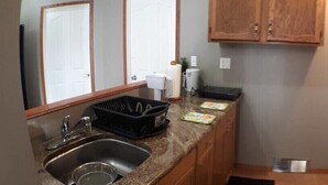 A compact kitchen with a sink, countertop, cabinets, and a microwave. - Bright, Welcoming Mountain Escape! Near Downtown! (Calgary)