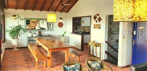 A dining area with a wooden table and benches, surrounded by potted plants and wicker chairs. - EXCELLENT HOUSE IN GERIBÁ, 500m FROM THE BEACH! BEAUTIFUL VIEW. 4 BEDROOMS, AIRY, COZY (Armação dos Búzios)