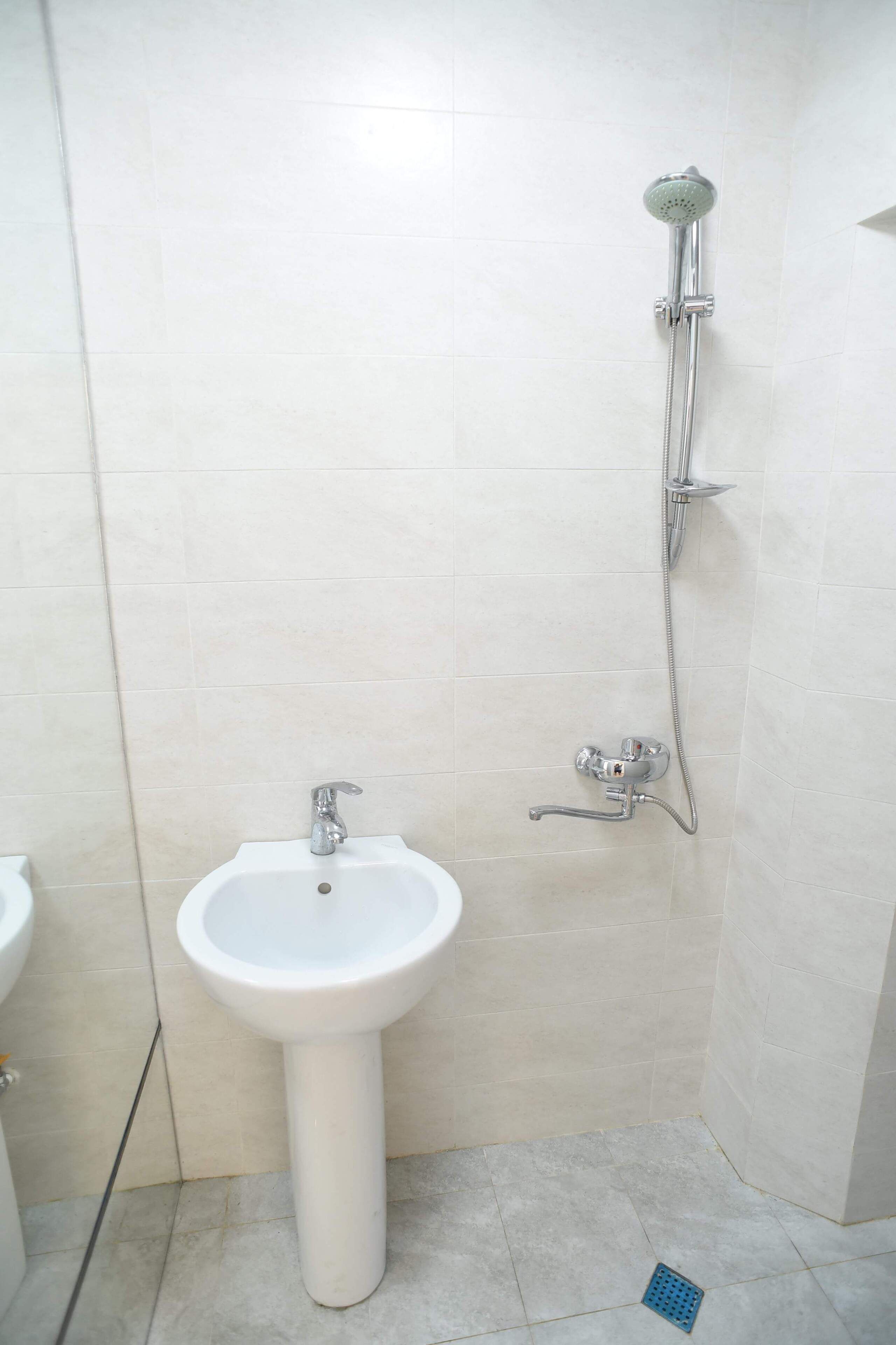 A bathroom with a pedestal sink and a wall-mounted shower.