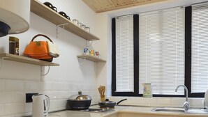 A compact kitchen with a washing machine, a sink, and wooden shelves. - Wine underground style appartment in the oldest town (Tbilisi)