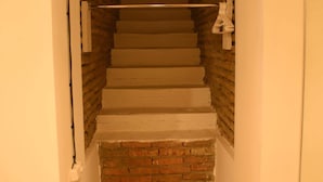 A narrow staircase with white steps leading up to a landing, flanked by brick walls and a wooden ceiling. - Wine underground style appartment in the oldest town (Tbilisi)