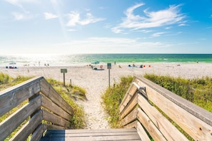Eine Holztreppe führt zu einem Sandstrand mit freiem Blick auf das Meer.