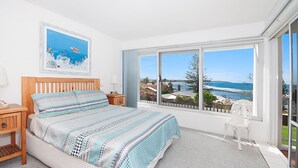 A bedroom with a large window offering a view of the sea and a coastal landscape. - Quarterdeck 4 @ Lennox Head (LENNOX HEAD)