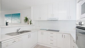 A modern kitchen with white cabinets, a Bosch dishwasher, a sink, and an oven. - Quarterdeck 4 @ Lennox Head (LENNOX HEAD)