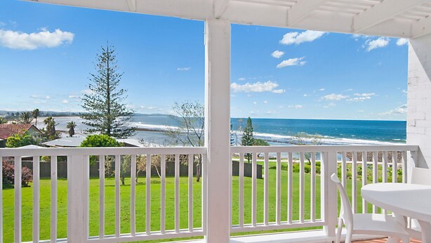 A covered patio with a view of the ocean, a grassy lawn, and a white fence. - Quarterdeck 4 @ Lennox Head (LENNOX HEAD)