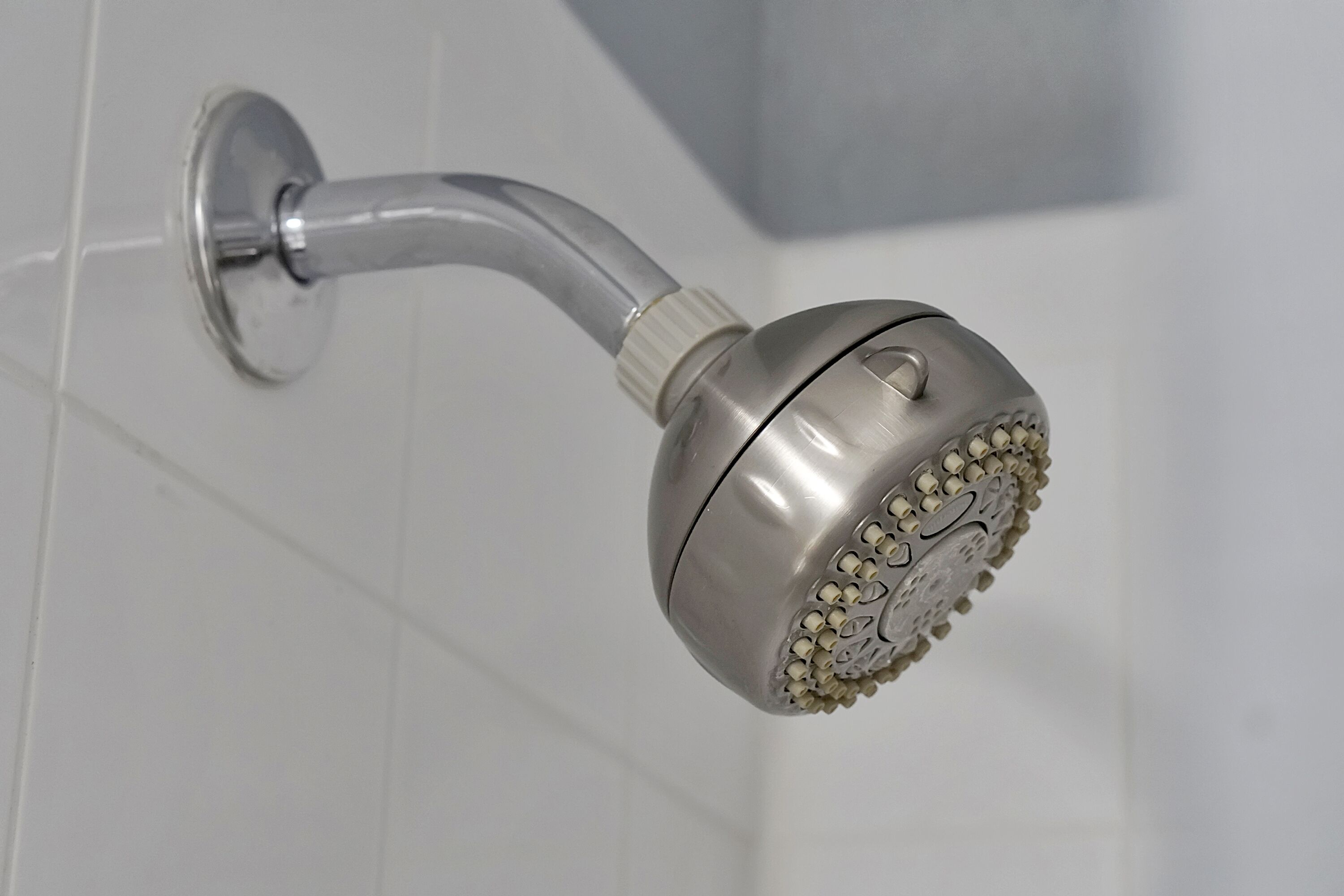 Un pommeau de douche fixé au mur, avec une finition chromée.